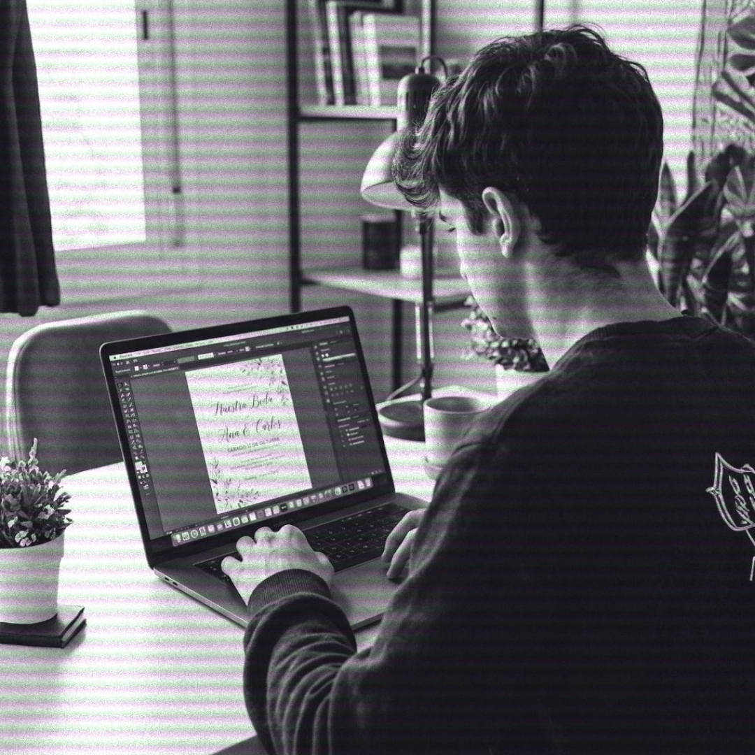 Juan designing the 'Ana & Carlos' wedding invitation website on a laptop